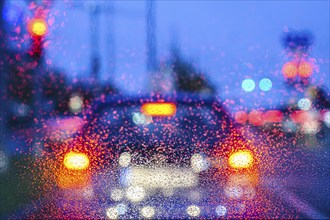 Blurred view of car lights at night through rain-soaked windows