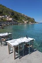 Inviting outdoor dining area overlooking the turquoise Mediterranean Sea next to a steep coastline,