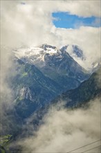 Mountain peaks, partly covered with snow, rise into a cloudy sky, Stilluptal, Zillertal. Austria