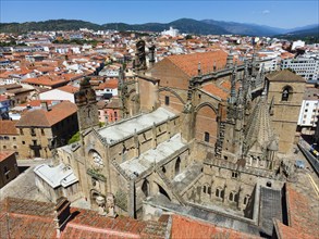 Gothic church and surrounding buildings with red tiled roofs in the city under a blue sky, aerial