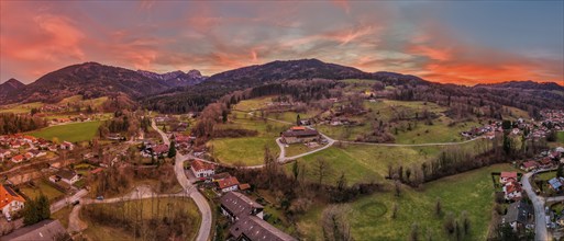 Panoramic view of a village in a hilly landscape at sunset with a red-coloured sky, Bad Feilnbach