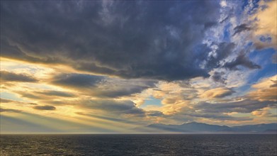 Dramatic sky over the sea with sun rays breaking through the clouds, Cape Melagkavi, Gulf of