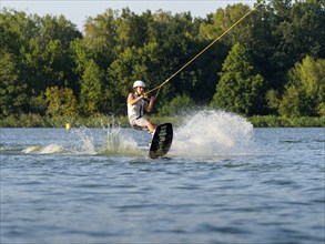 Young man with wakeboard, jump in lake, water sports, water skiing in wakepark