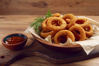 Deep fried onion rings, appetizer, with tomato sauce, on a wooden table, no people, favorite dish