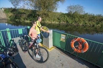 Cyclist, cycle tour, manually operated ferry across the Lippe near Halten am See, on the