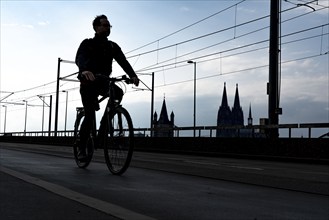 Cycling in the city, cyclist on the Deutzer Bridge in Cologne, Cologne Cathedral, cycle path, North