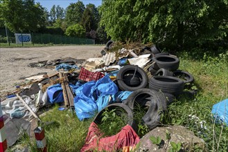 Illegally disposed waste, car tyres, building rubble, household waste, clothing, on a path next to