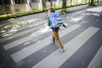 Symbol photo on the subject of schoolchildren in road traffic A six-year-old boy walks across the