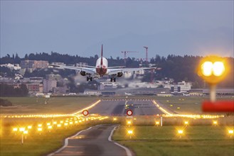 Helvetic Airways aircraft landing in the evening with illuminated runway. Zurich Airport,