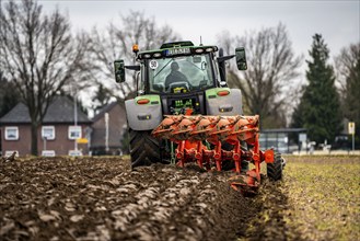 Tractor with a plough preparing the soil of a field for planting, Agriculture, Spring