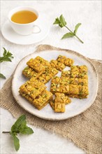 Traditional iranian dessert sohan with cup of green tea on a gray concrete background and linen