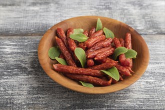 Small smoked sausage with borage microgreen, salt and pepper on gray wooden background. Side view,