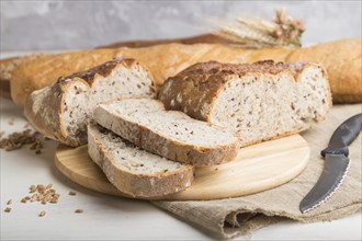 Sliced bread with different kinds of fresh baked bread on a white wooden background. side view,