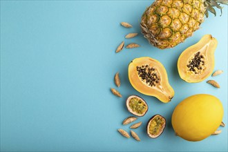 Ripe cut papaya, pineapple, melon, passion fruit, almonds on blue pastel background. Top view, flat