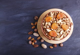 Mixed different kinds of nuts in ceramic bowl on black wooden background with copy space. hazelnut,