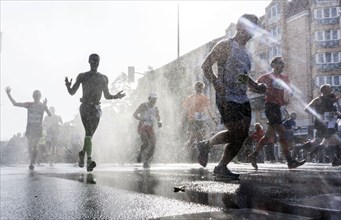 The participants of the Berlin Marathon are cooled down with a water shower in the Schöneberg