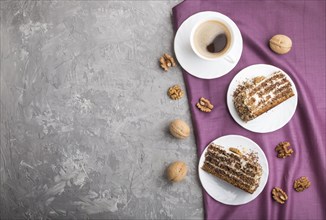 Homemade cake with milk cream and walnuts with cup of coffee on a gray concrete background and