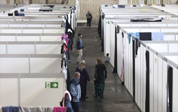 Children of refugees look over the wall of a temporary room in an emergency shelter for refugees on