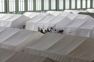 Tents with beds are set up in an emergency shelter for refugees on 9 December 2015 in a former