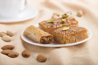 Traditional arabic sweets (basbus, kunafa, baklava) and a cup of coffee on a gray concrete