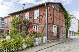 A picturesque half-timbered house with flowering plants and surrounded by cobbled streets, Rügen