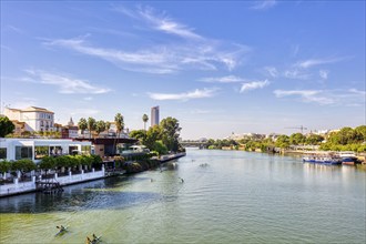 River with canoes and lively promenade on a sunny day, Seville