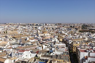 Sweeping view over the rooftops of a large city under a clear sky, Seville