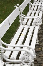 Old white painted wood and tubular steel sitting benches in a row, Prague Castle district, Prague,