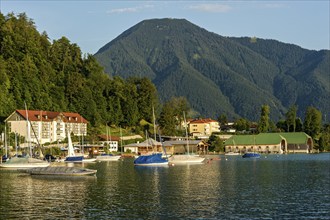 Tegernsee with sailing boats and boat huts, warm evening light, town Tegernsee, mountain Wallberg,