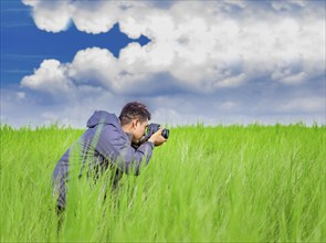 Man taking picture with camera in the field, photographer in the field taking a picture, Latino man