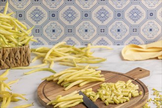 Sliced yellow beans on a wooden chopping board, whole runner beans in the background