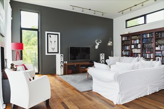 Living room with Qumaru wood floorboards, white leather armchairs, sofas, home entertainment sound