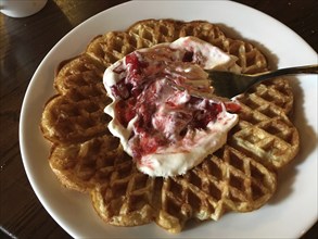 A crispy waffle with cream and strawberries served on a plate, Norwegian national dish, Restaurant,