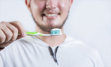 Hand of man showing toothbrush with toothpaste isolated. Close up of hands holding brush with