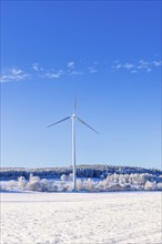 Wind turbines in a field in a cold snowy winter landscape with a clear blue sky, Sweden, Europe