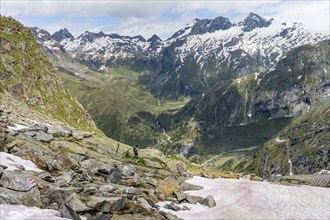 Mountaineer on a hiking trail in front of a picturesque mountain landscape, rocky mountain peaks