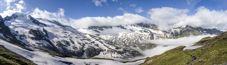 Mountaineer on hiking trail, mountain panorama with high fog in the valley, summit Hochfeiler,