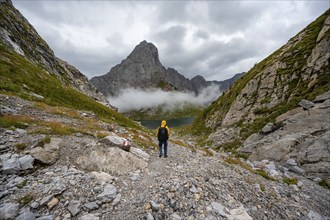 Mountaineers on a hiking trail with a view of rocky cloudy mountains and Wolayersee, hiking trail