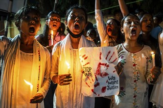 Students holds candle and shout slogans as they participate in a protest against the rape and