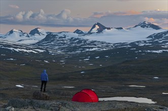 Hiker looks out from his tent towards the Sulitelma massif with the Sulitelma glacier, Laponia