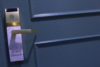 Blue painted door with 'Do Not Disturb' sign and gold-coloured handle in a hotel