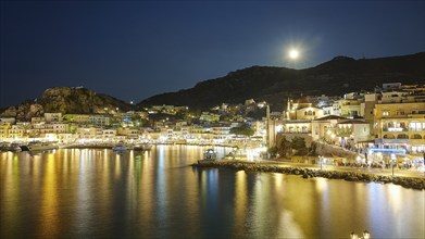 Illuminated coastal town with full moon and water at night, Rising full moon, Pigadia, town and