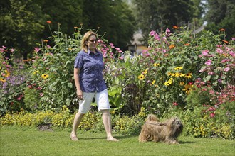 Woman takes Lhasa Apso for a walk in the park