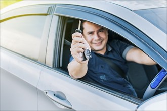 Person in his vehicle showing his car keys, A man in his vehicle showing his new car keys, a happy