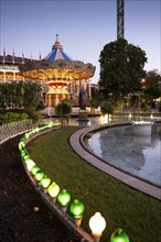 Illuminated historical carousel, garden with pond and lights, dusk, Tivoli Amusement and Recreation