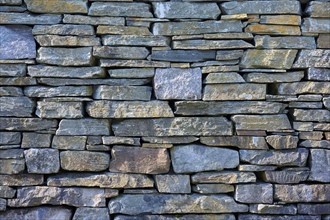 Large, irregular natural stones in various shades of grey form a rustic stone wall, Bergen,