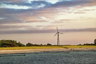 Sunset on the Baltic Sea beach, Wustrow beach in the evening light with clouds and windmill,