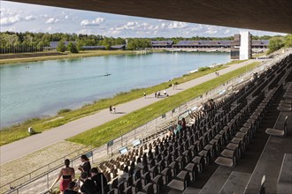 View from the grandstand of a lake with paddlers, surrounded by a natural landscape,