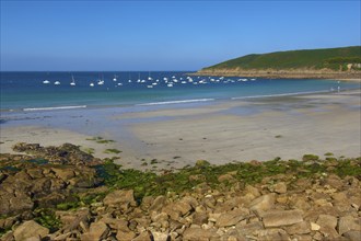 Quiet beach with many boats on the blue sea and rocks in the foreground, Brittany, France, Europe