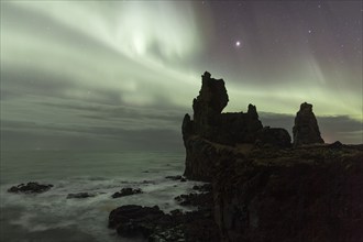 Northern lights or aurora borealis, starry sky, rocky coast, silhouette basalt rock Lóndrangar or